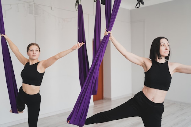 Adorables femmes faisant du yoga aérien dans un club de sport