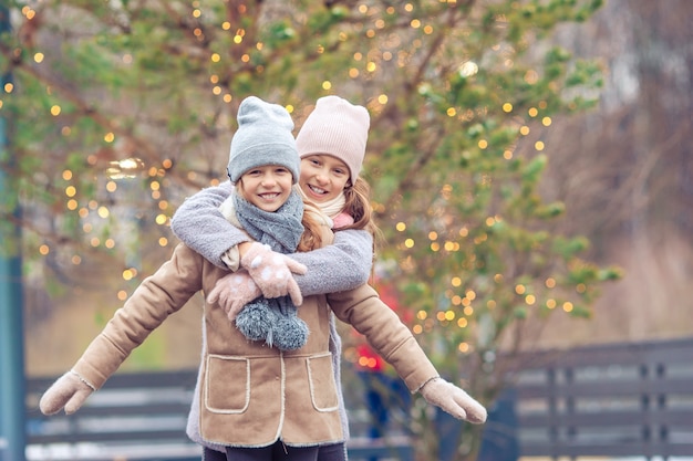 Adorables filles patinant sur la patinoire à l'extérieur en hiver journée de neige