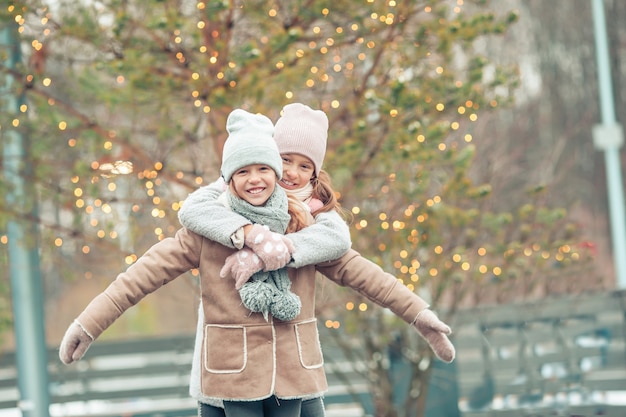 Adorables filles patinant sur la patinoire à l'extérieur en hiver journée de neige