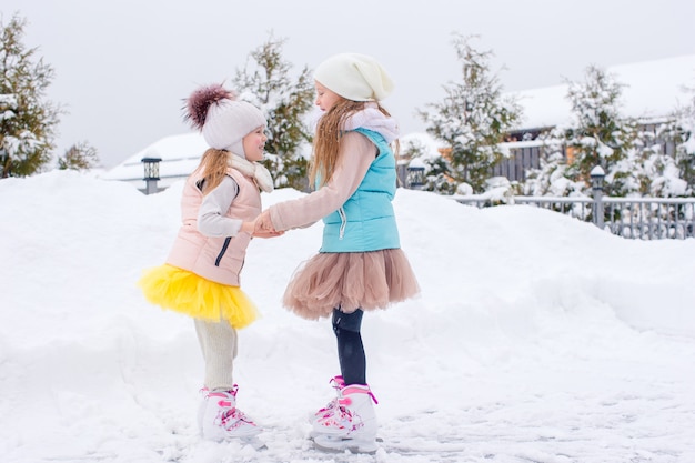 Adorables filles patiner sur la patinoire à l'extérieur en hiver