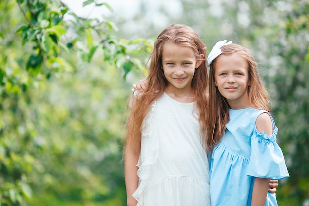 Adorables petites filles dans le jardin de pommiers en fleurs le jour du printemps