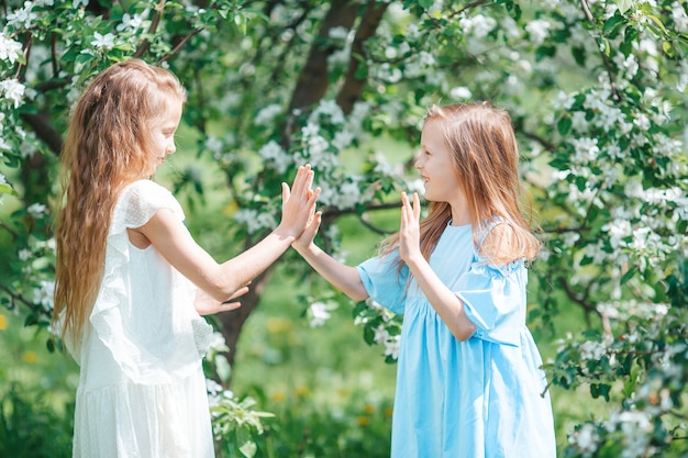 Adorables petites filles dans le jardin de pommiers en fleurs le jour du printemps