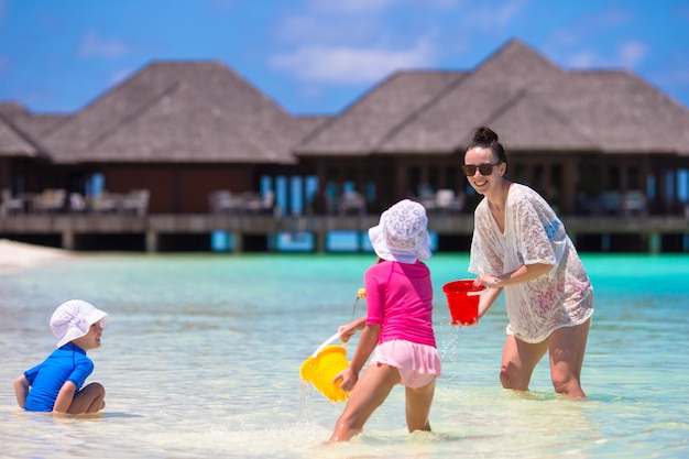 Adorables petites filles et heureuse mère jouant avec des jouets de plage en vacances d'été