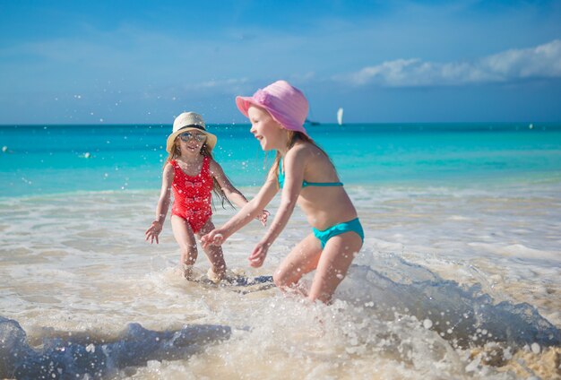 Adorables petites filles jouant dans des eaux peu profondes à la plage exotique