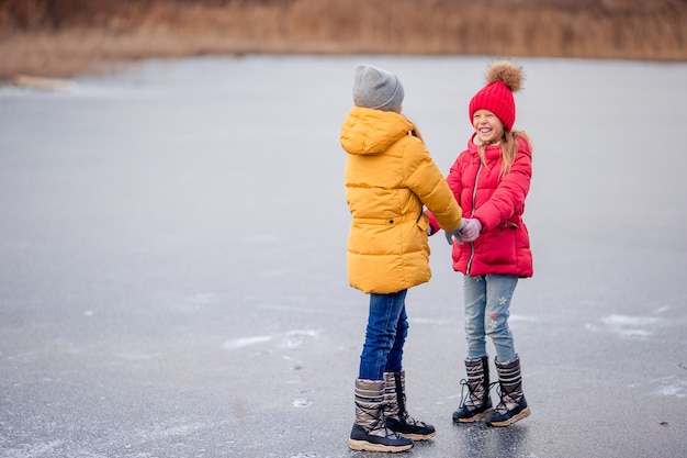 Adorables petites filles s'amusant ensemble sur un lac gelé