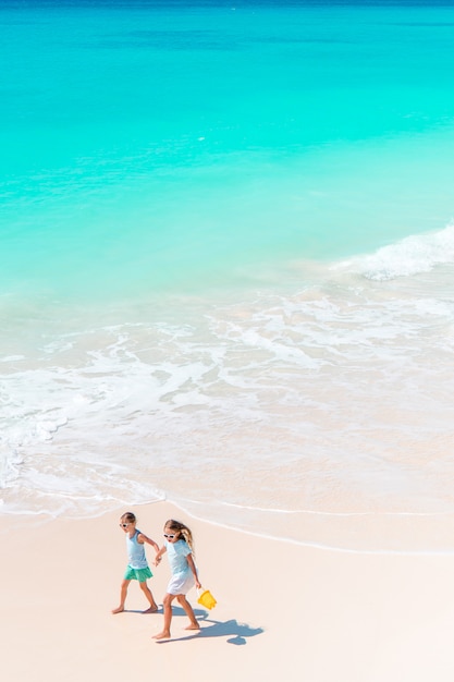 Les adorables petites filles s'amusent beaucoup sur la plage.