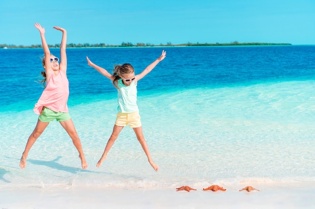 Les adorables petites filles s'amusent beaucoup sur la plage.