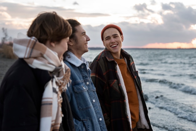 Photo ados souriants à plan moyen au bord de la mer