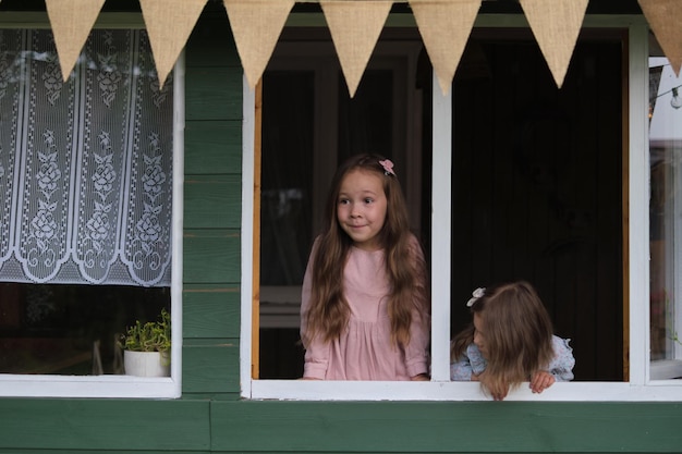 Adossé à une serre rustique, deux jeunes filles boivent dans les images et les sons d'une cour luxuriante