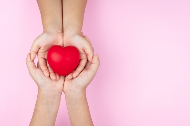 Adulte et enfant mains tenant coeur rouge