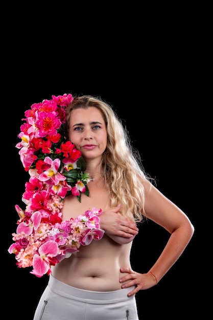 Adulte jeune femme avec bras couvert de fleurs symbolisant le concept de terre mère sur un fond noir.