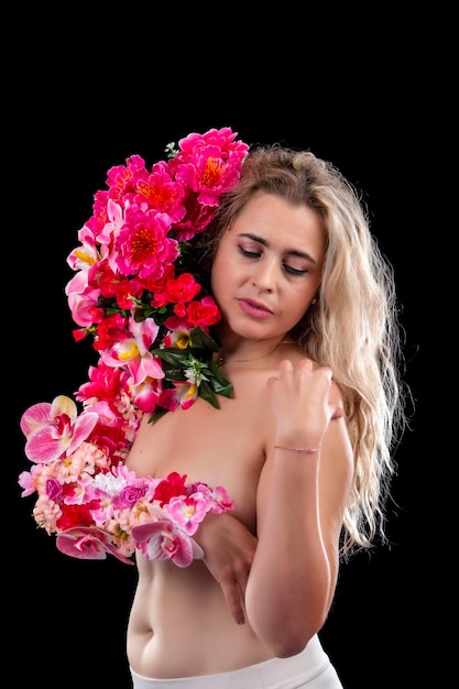 Adulte jeune femme avec bras couvert de fleurs symbolisant le concept de terre mère sur un fond noir.