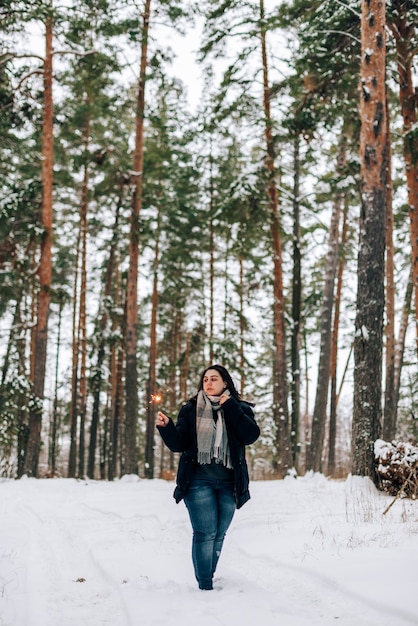 Adulte jeune femme avec des cierges sur la forêt de pins d'hiver