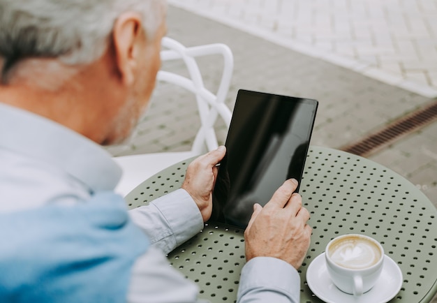 Adulte mature à l'aide de sa tablette dans un café-bar