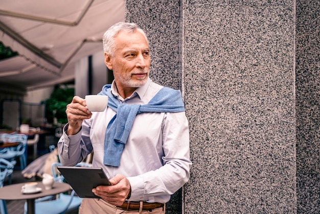 Adulte mature à l'aide de sa tablette dans un café-bar