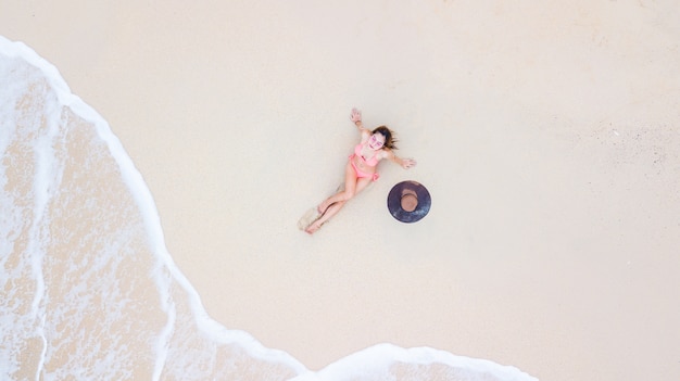 Aerial vue de dessus jeune femme en bikini couché sur la plage de sable et les vagues