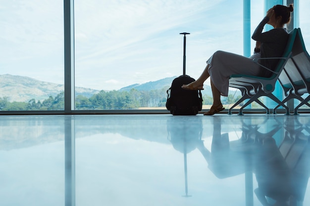 Aéroport vide avec femme touristique en attente de retard avion appel avec bagages. Annulations de vol et concept de voyage. Tourisme et vacances lifestyle en Europe.