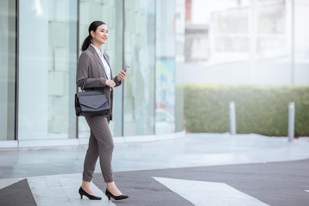 Affaires asiatiques marchant dans une suite décontractée avec téléphone intelligent femme asiatique avec smartphone