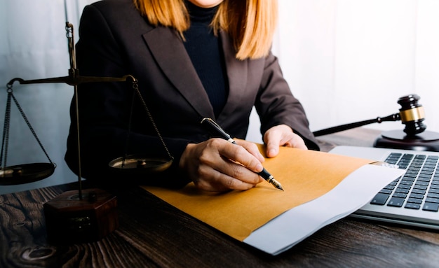 Affaires et avocats discutant des documents contractuels avec une échelle en laiton sur le bureau au bureau