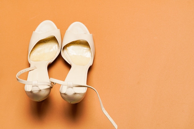 Affaires en cuir blanc ou chaussures de soirée pour femmes sur fond marron avec espace de copie. vue de dessus à plat.