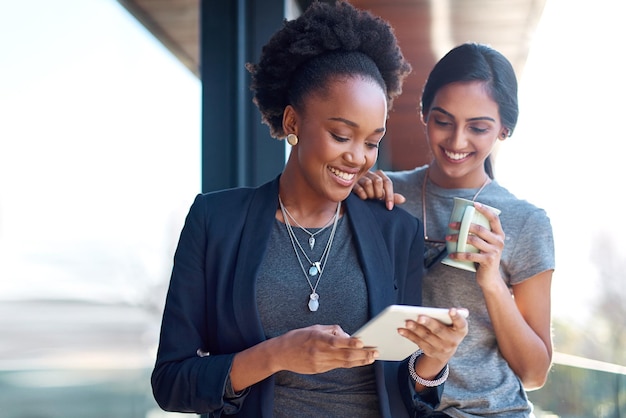 Affaires et un peu d'air frais pendant leur pause Photo de deux jeunes collègues utilisant une tablette numérique ensemble au travail