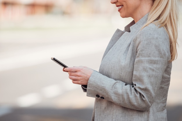 Affaires positives en utilisant un téléphone intelligent à l&#39;extérieur, gros plan.