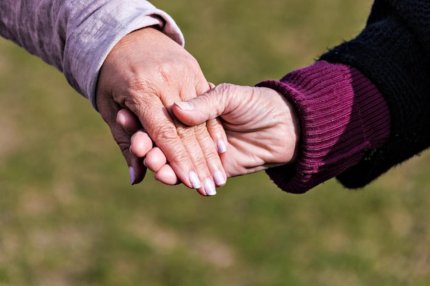 Affection et tendresse d'une petite-fille à sa grand-mère. Traits de vieillissement sur les mains.