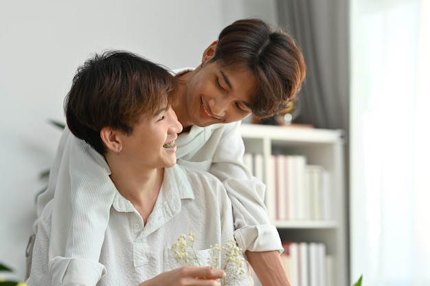 Affectueux couple gay masculin romantique passant du temps ensemble en appréciant l'arrangement de fleurs dans une maison confortable LGBT homosexuel et amour