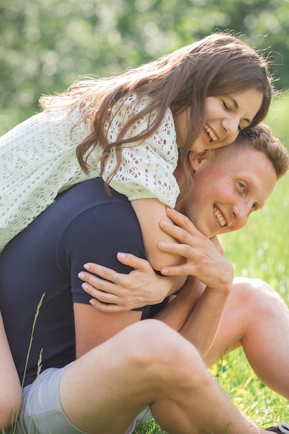 Affectueux jeune couple assis sur l'herbe dans le parc à la recherche sur l'autre jeune homme et femme enjoyin