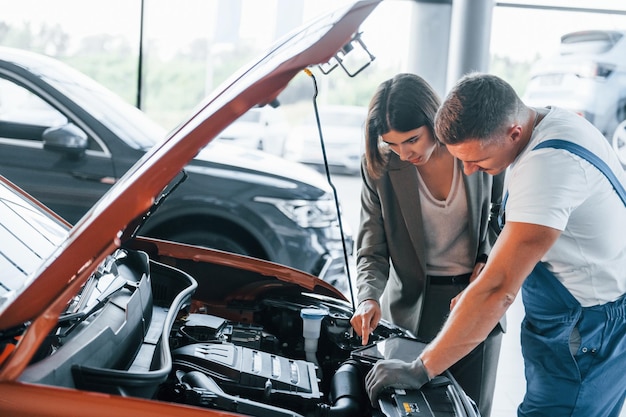 Affichage des résultats du travail Homme réparant l'automobile de la femme à l'intérieur Service professionnel