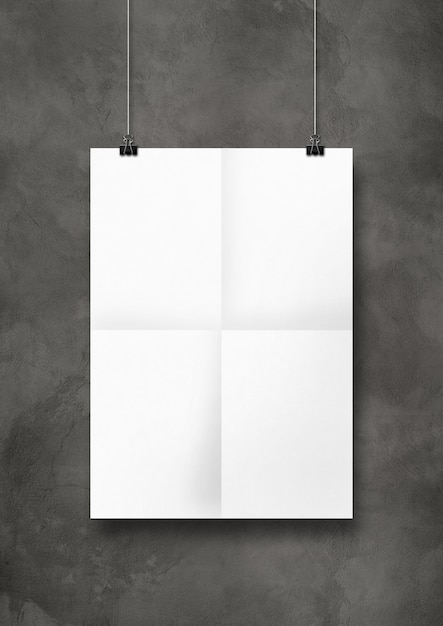 Affiche pliée blanche accrochée à un mur de béton avec des clips