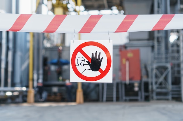 Une affiche de la zone interdite sur un ruban rouge et blanc clôturant le passage sur fond de canalisations de la centrale. Les personnes non autorisées ne sont pas autorisées à entrer dans l'usine