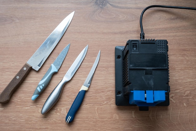 Affûtage d'un couteau sur un affûteur électrique à la maison Lame de couteau Flatlay aiguiseurs de ciseaux la poussière vole sur la machine