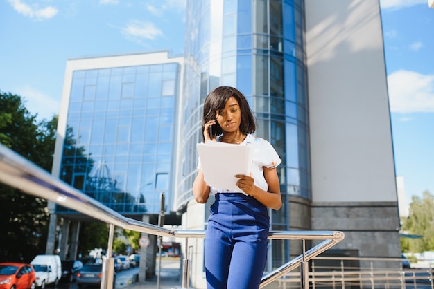 African American businesswoman using mobile phone contre building