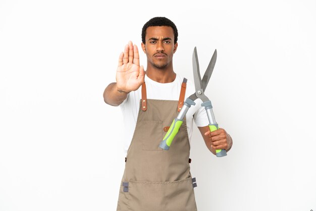 African American gardener man holding sécateur sur fond blanc isolé faisant un geste d'arrêt