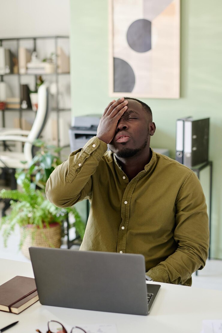 Un Afro-Américain assis dans un bureau la tête dans la main