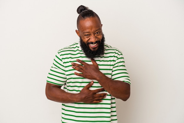 Un afro-américain à la barbe isolé sur un mur rose rit joyeusement et s'amuse à garder les mains sur le ventre.