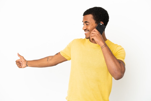 Afro-américain bel homme utilisant un téléphone portable sur fond blanc isolé donnant un geste du pouce vers le haut