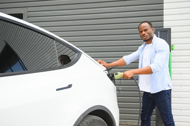 Photo un afro-américain charge sa voiture électrique.