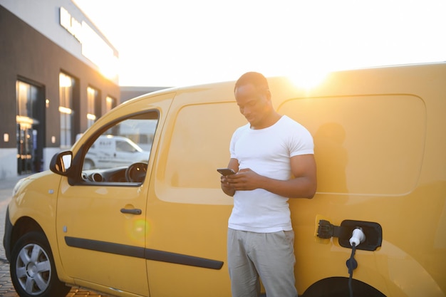 Photo un afro-américain charge sa voiture électrique.