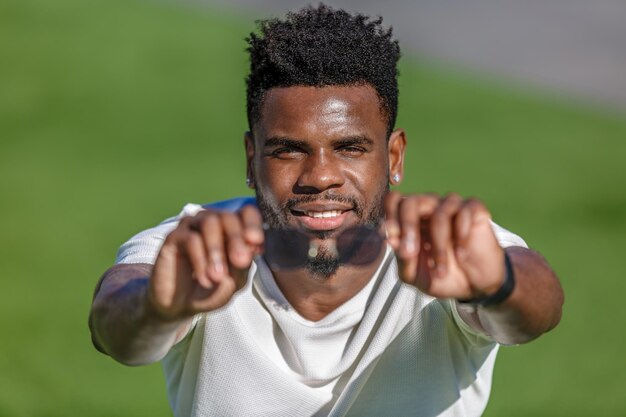 Un Afro-Américain en chemise blanche avec les mains tendues tenant des lunettes de soleil