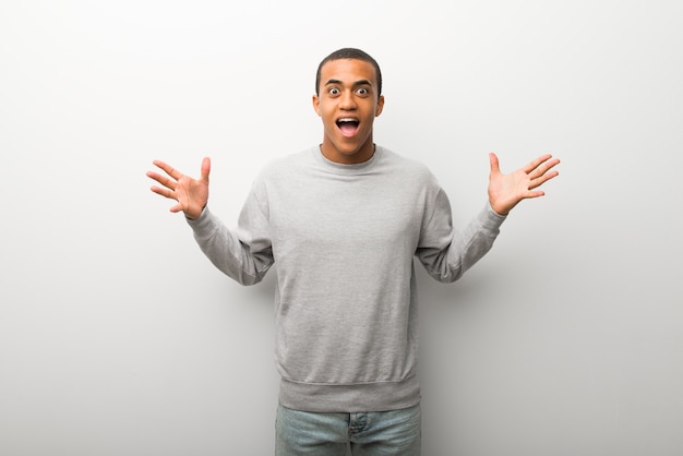 Afro-américain sur fond de mur blanc avec une expression faciale surprise et choquée