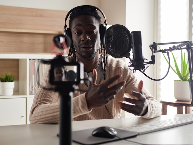 Photo afro-américain heureux jeune homme enregistrant un blog audio dans un casque microphone diffusant à la maison
