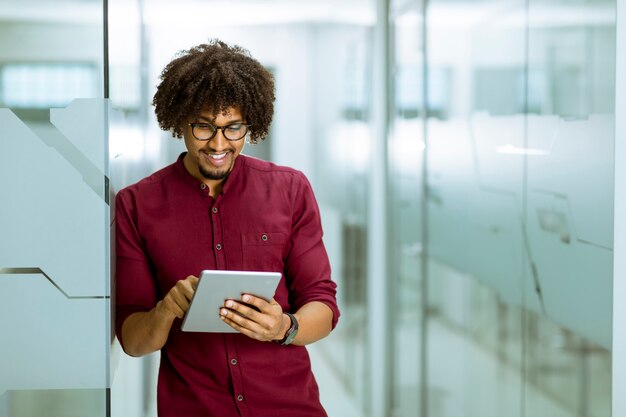 Afro-américain jeune homme d&#39;affaires avec une tablette debout dans le bureau