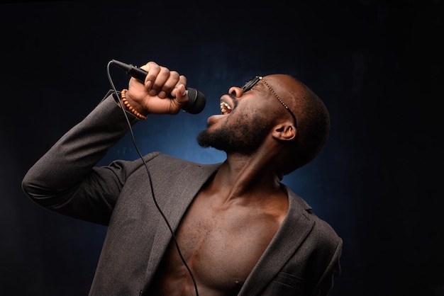 Un afro-américain noir chante avec émotion dans un microphone Closeup studio portrait