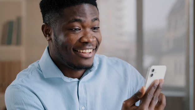 Afro-américain surpris homme d'affaires millénaire s employé propriétaire tenir gadget mobile moderne