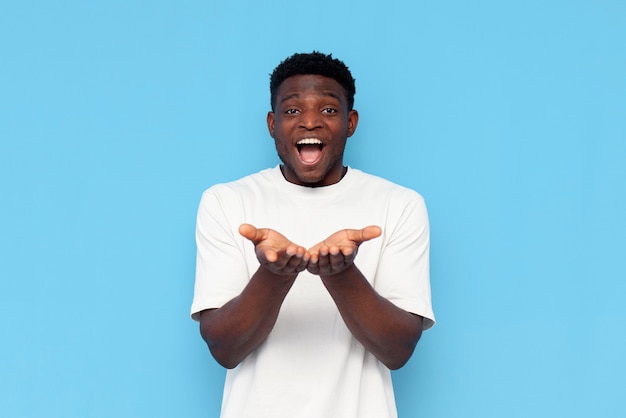 un afro-américain en t-shirt blanc tient les mains vides devant lui et se réjouit