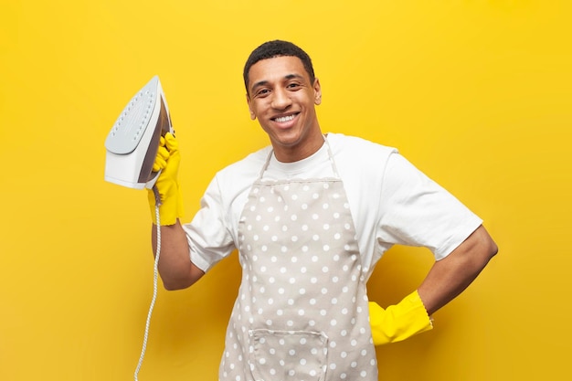 Un afro-américain en tablier et gants tient du fer sur fond isolé jaune