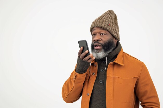 Un Afro-Américain avec un téléphone sur un fond de studio blanc.