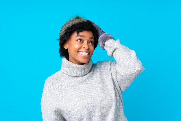 Afro-américaine avec chapeau d'hiver sur mur bleu